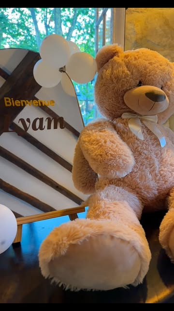 Décor de fête de naissance monté par Eterna Event : panneau de bienvenue au prénom de l'enfant, ballons blancs et grand ours en peluche